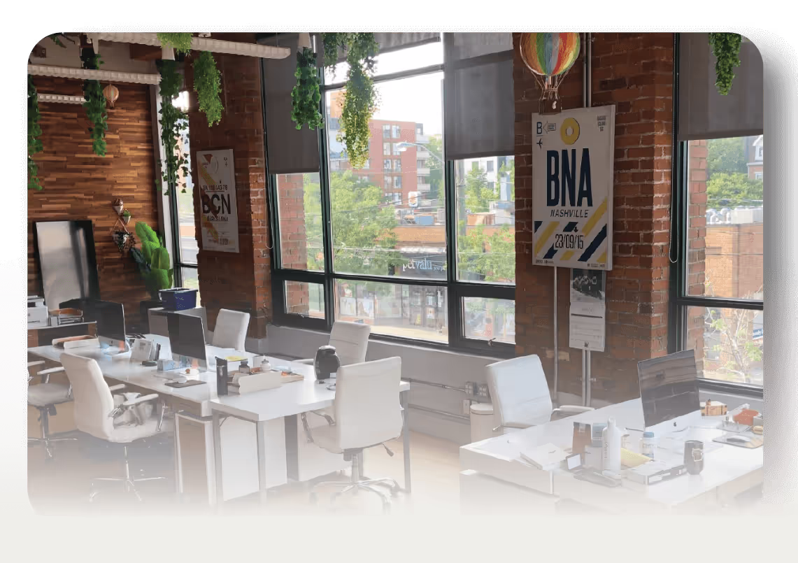 Modern office with brick walls, white desks, and Nashville airport poster